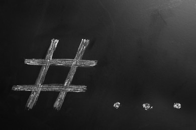 Photo of Hashtag symbol and ellipsis drawn with chalk on blackboard. Space for text