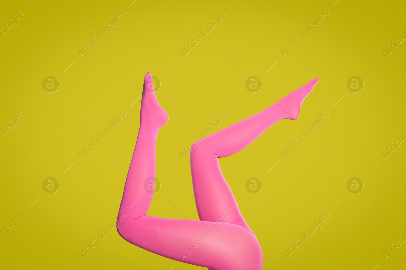 Photo of Woman wearing pink tights on yellow background, closeup of legs