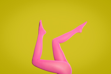 Woman wearing pink tights on yellow background, closeup of legs