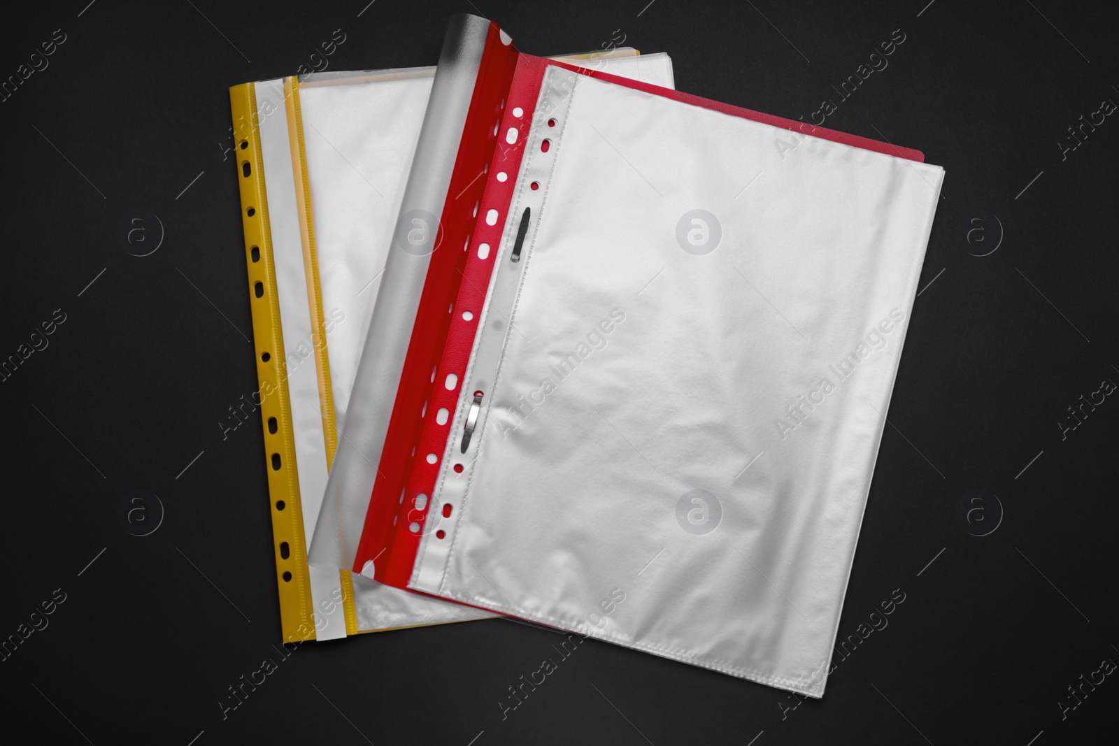 Photo of File folders with punched pockets and paper sheets on black background, flat lay. Space for text