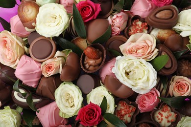 Beautiful bouquet of flowers and chocolate candies as background, closeup