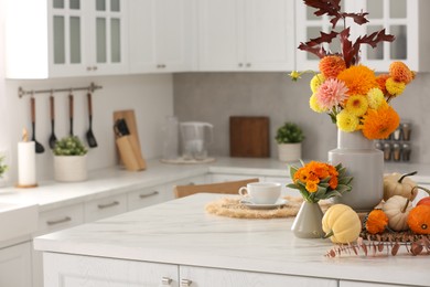 Photo of Beautiful autumn bouquets and pumpkins on marble table in kitchen