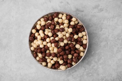 Tasty cereal balls in bowl on grey table, top view