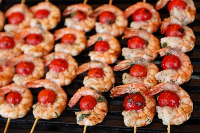 Photo of Delicious fresh shrimp skewers with cherry tomatoes on grill, closeup