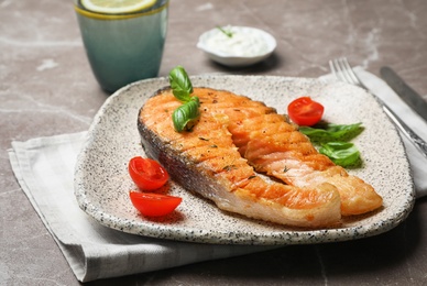 Plate with tasty salmon steak on grey background