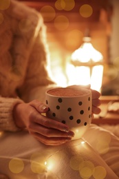 Photo of Woman with cup of hot drink at home, closeup. Christmas celebration