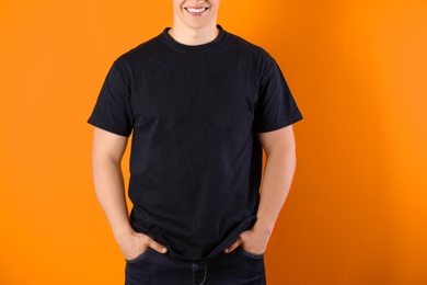 Photo of Young man in black t-shirt on color background. Mockup for design