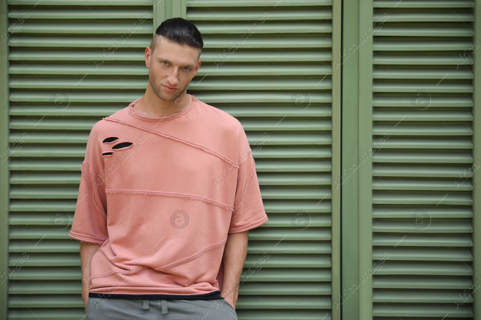 Photo of Handsome young man in stylish outfit near shutters, space for text