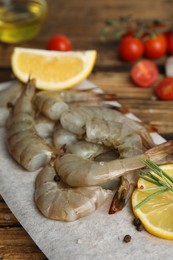 Fresh raw shrimps with lemon on wooden board, closeup