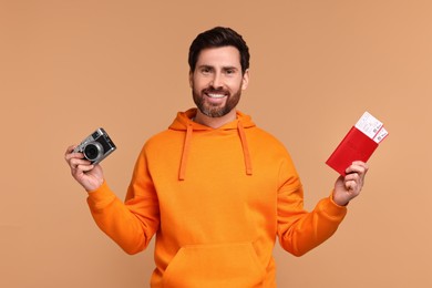 Photo of Smiling man with passport, camera and tickets on beige background