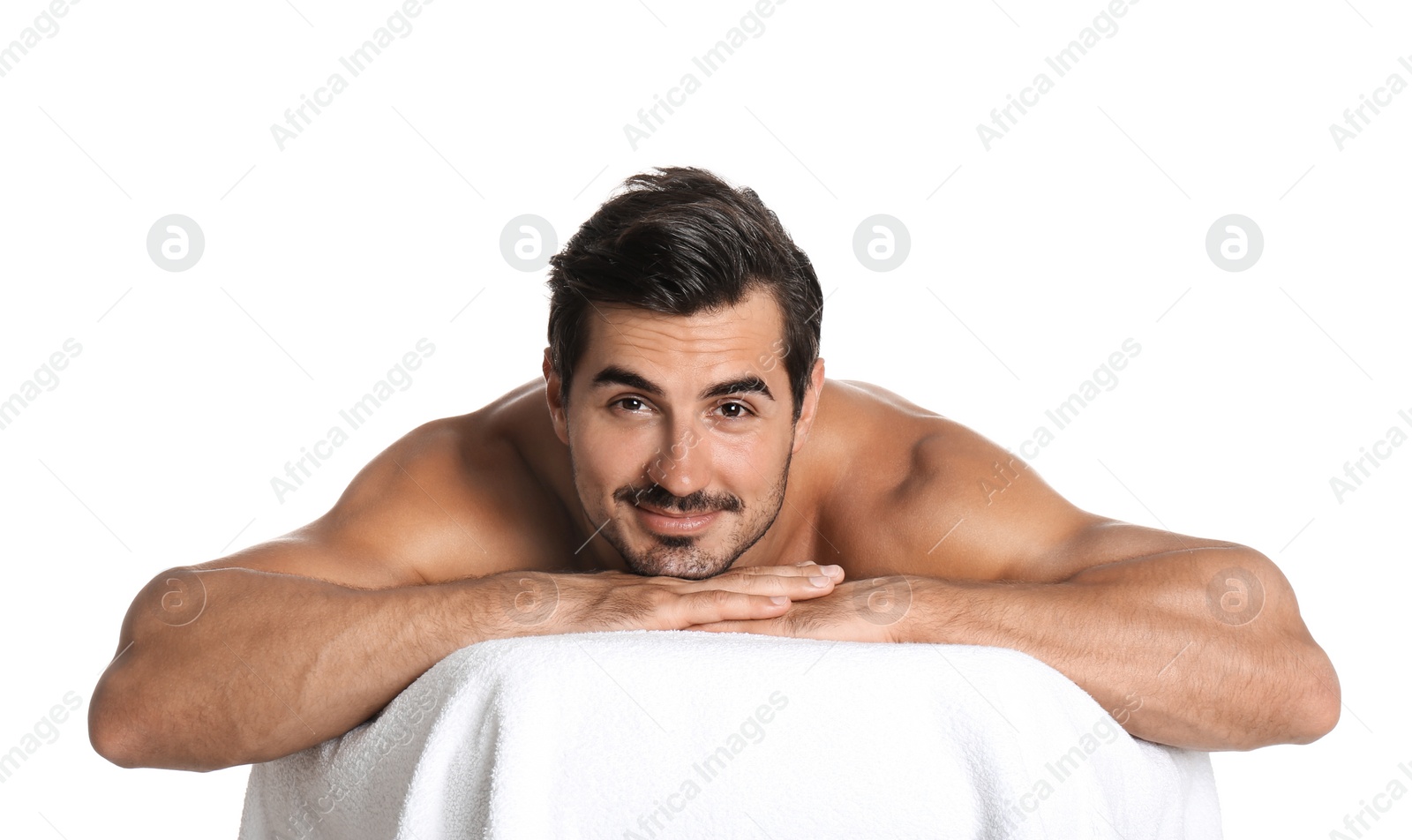 Photo of Handsome young man relaxing on massage table against white background. Spa salon