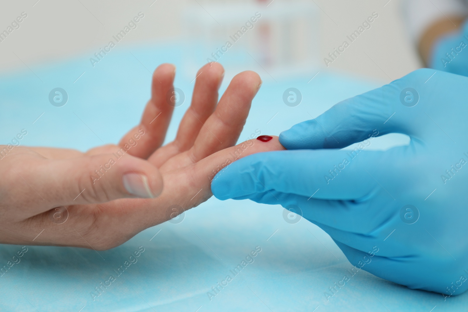 Photo of Doctor taking blood sample from patient's finger at table, closeup