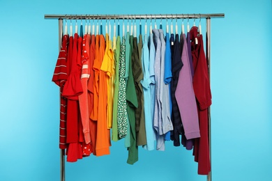 Photo of Wardrobe rack with different bright clothes on color background