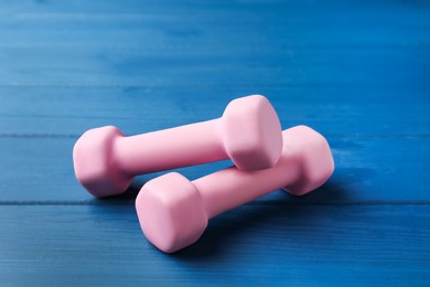 Photo of Pink rubber coated dumbbells on blue wooden table
