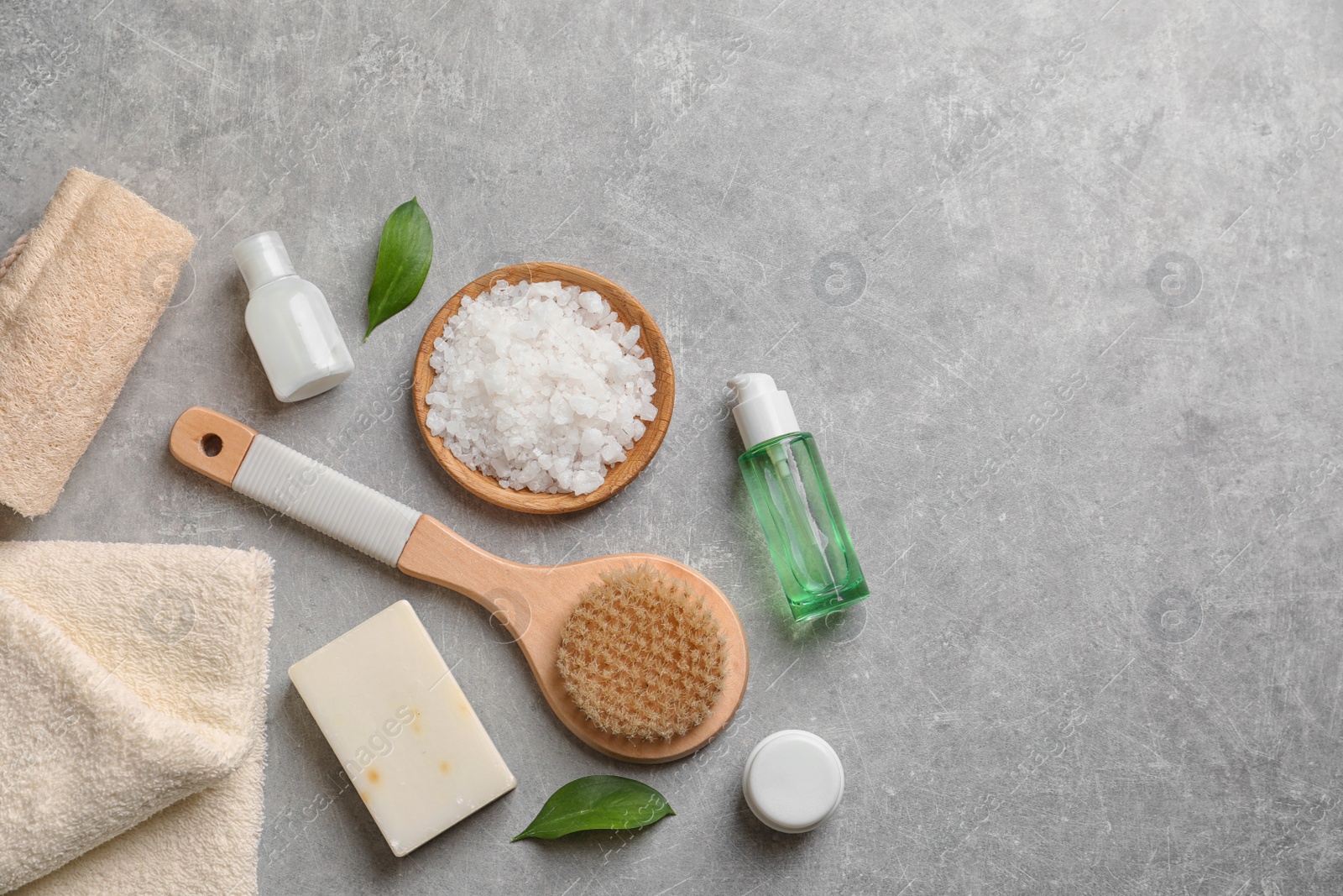 Photo of Flat lay composition with spa cosmetics and towel on grey background