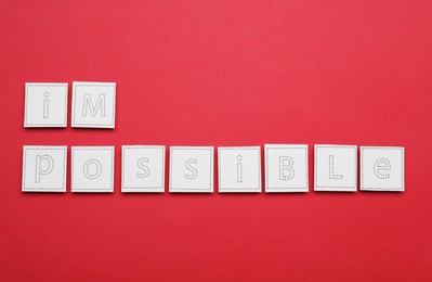 Photo of Motivation concept. Changing word from Impossible into Possible by removing paper on red background, flat lay