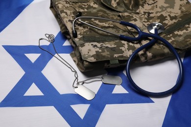 Photo of Stethoscope, tags and military uniform on flag of Israel