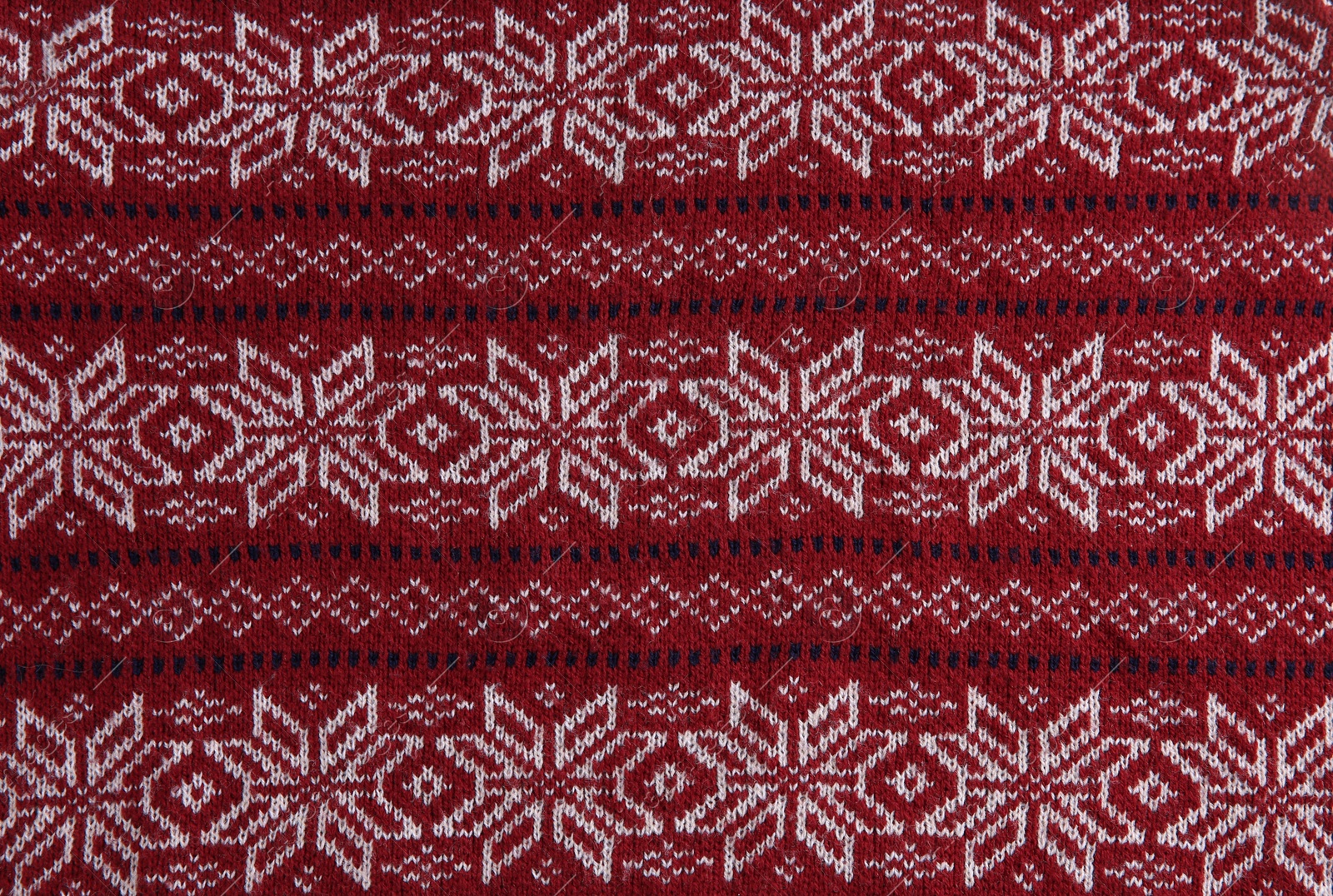 Photo of Christmas sweater with pattern as background, top view. Seasonal clothing