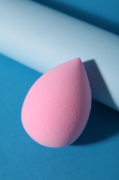 Photo of Pink makeup sponge on light blue background, closeup