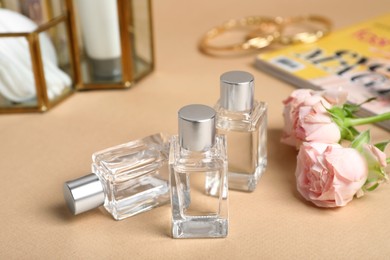 Photo of Perfumes and rose flowers on beige table