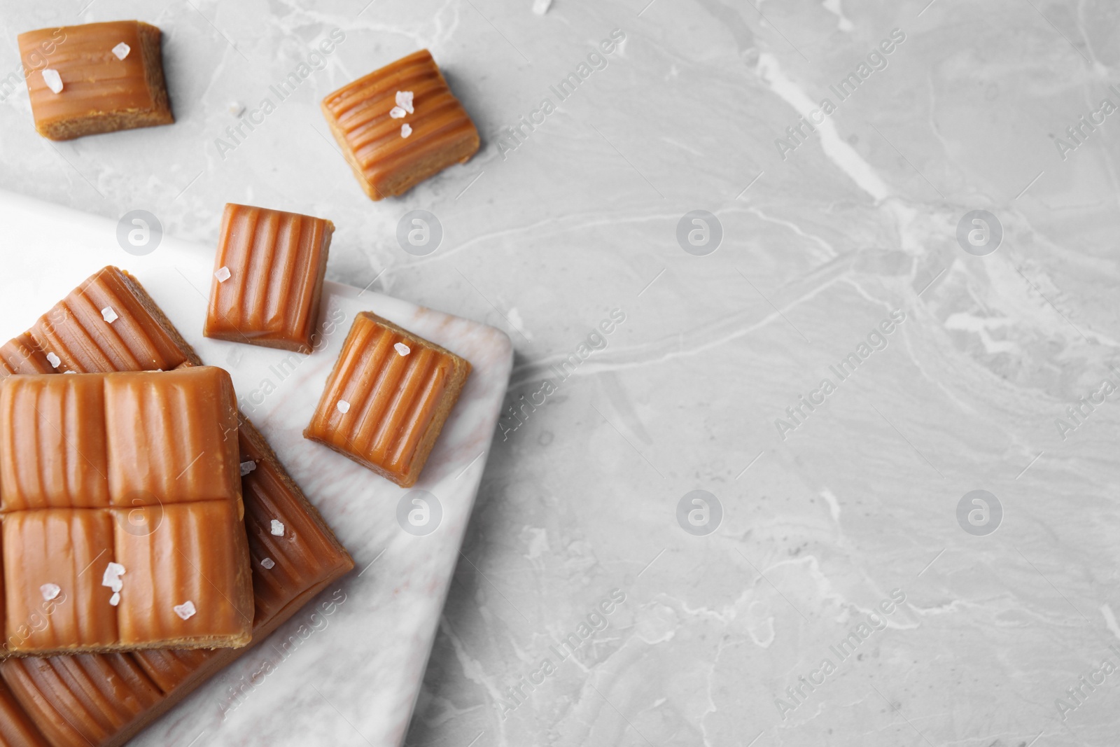 Photo of Salted caramel on marble table, flat lay. Space for text