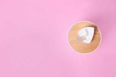 Photo of Holder with paper tissues on pink background, top view. Space for text