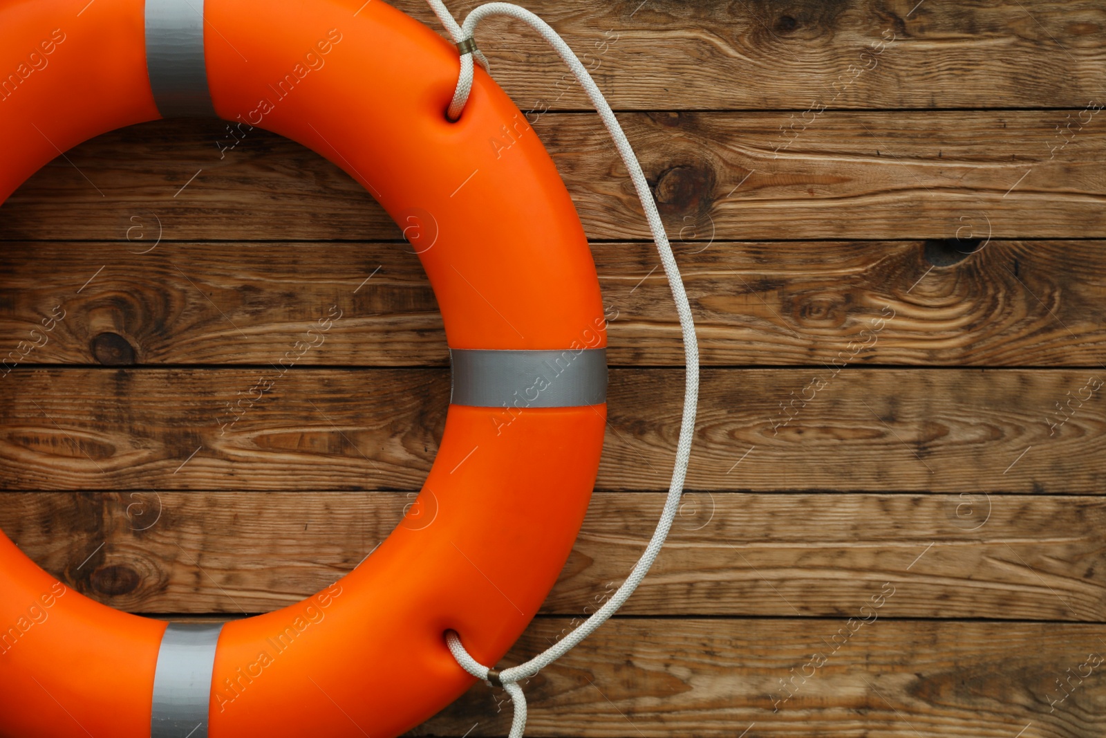 Photo of Orange lifebuoy on wooden background, space for text. Rescue equipment