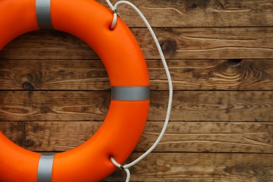 Photo of Orange lifebuoy on wooden background, space for text. Rescue equipment