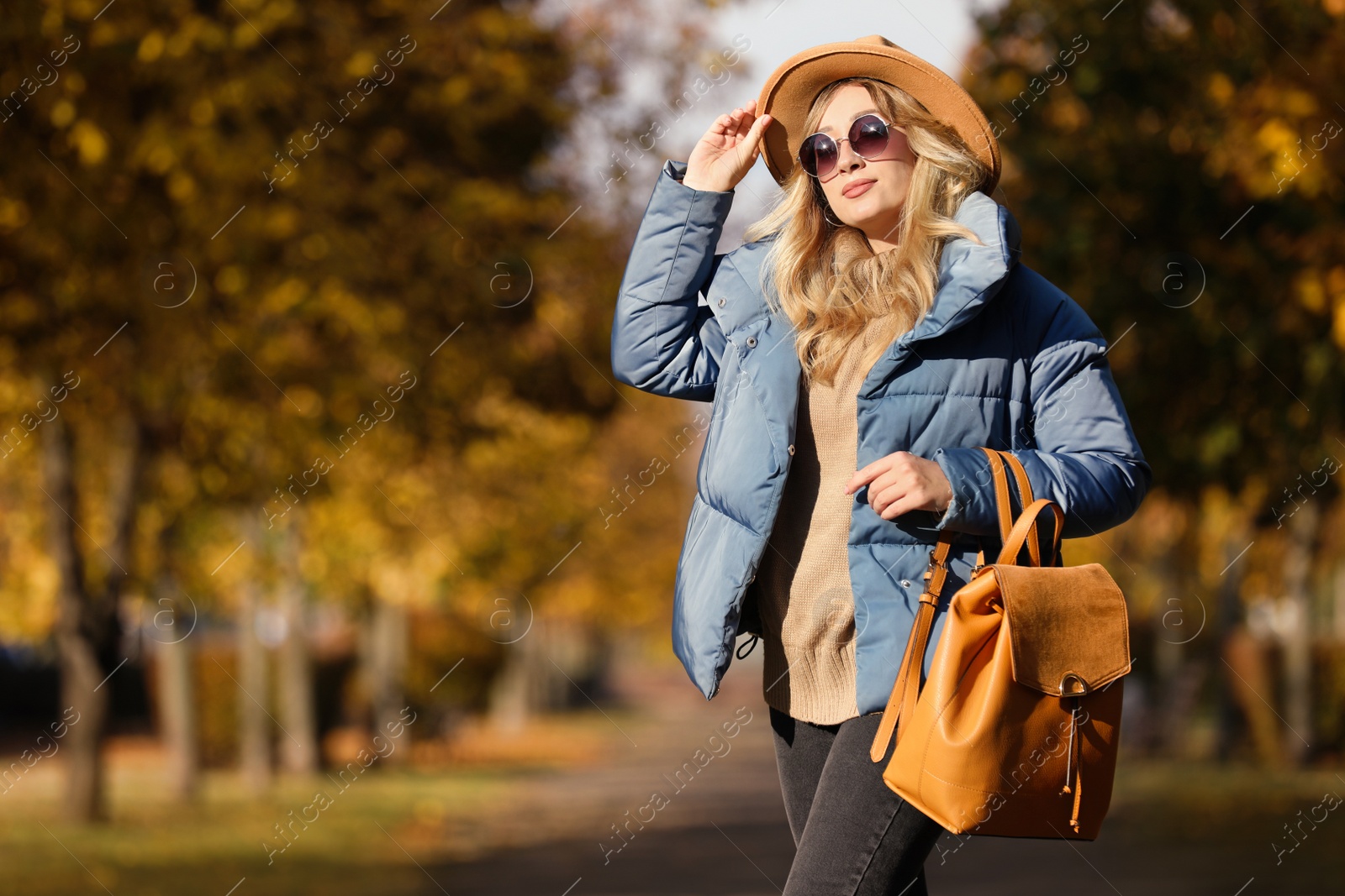 Photo of Young woman with stylish backpack on autumn day, space for text