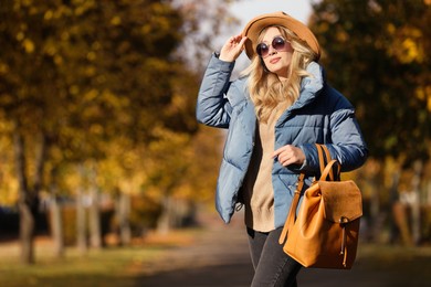 Photo of Young woman with stylish backpack on autumn day, space for text