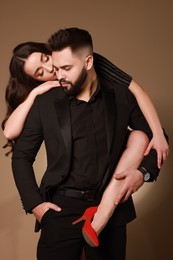 Handsome bearded man with sexy lady on light brown background