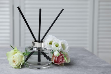 Photo of Reed air freshener and flowers on grey table indoors