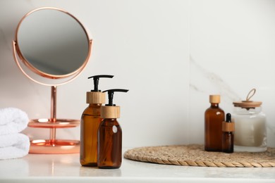 Photo of Glass bottles with dispenser caps on table in bathroom