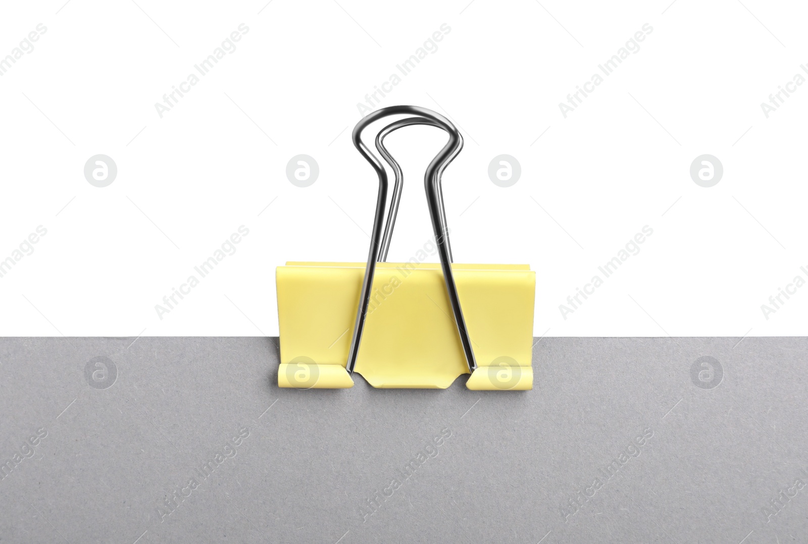 Photo of Grey paper with yellow binder clip isolated on white