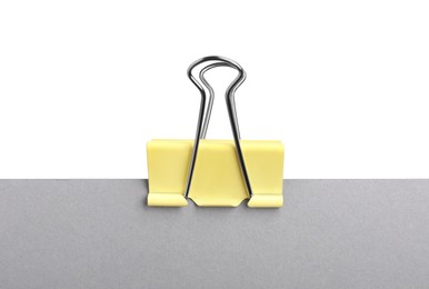 Photo of Grey paper with yellow binder clip isolated on white