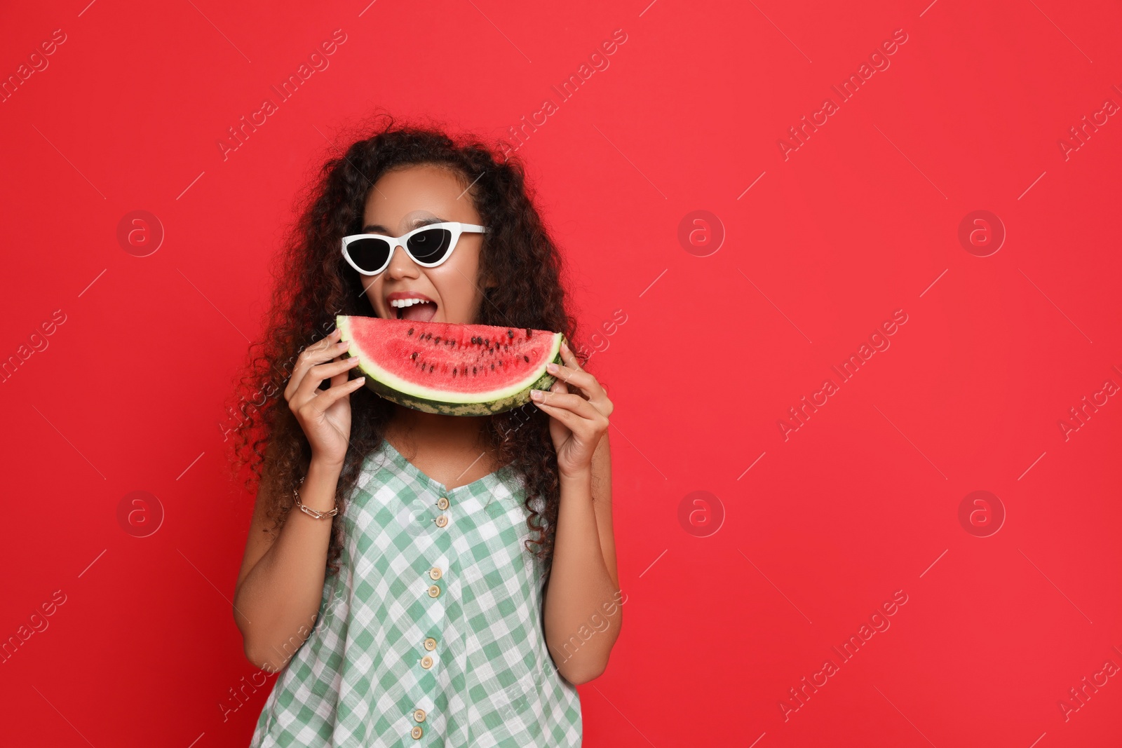 Photo of Beautiful young African American woman with slice of watermelon on red background. Space for text