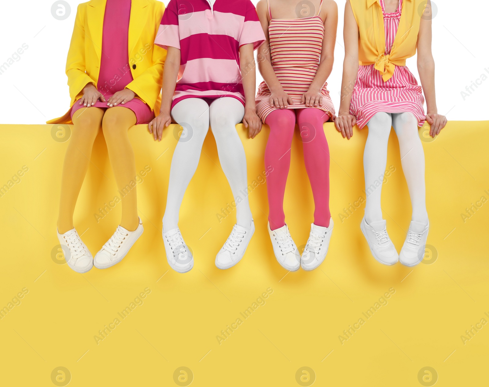 Photo of Women wearing bright tights sitting on color background, closeup