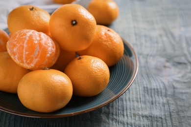 Photo of Fresh tangerines on blue wooden table. Citrus fruit