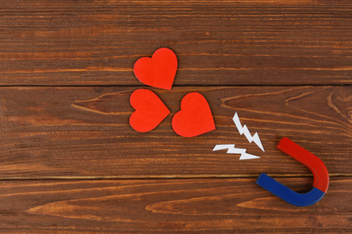 Photo of Magnet and red hearts on wooden table, flat lay