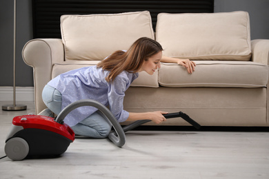 Young woman using vacuum cleaner at home