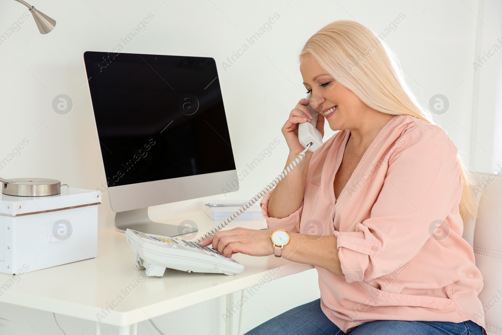 Photo of Mature woman talking on phone at workplace