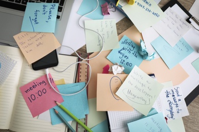Photo of Laptop, notes and office stationery in mess on desk, top view. Overwhelmed with work