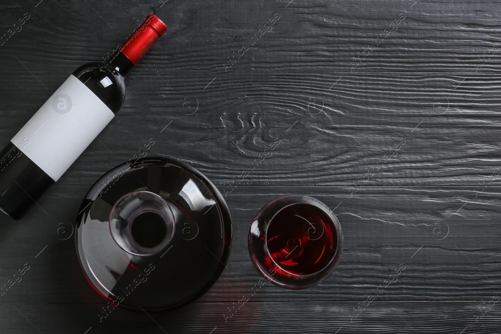 Photo of Decanter, glass and bottle with red wine on wooden background, top view