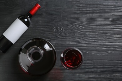 Photo of Decanter, glass and bottle with red wine on wooden background, top view
