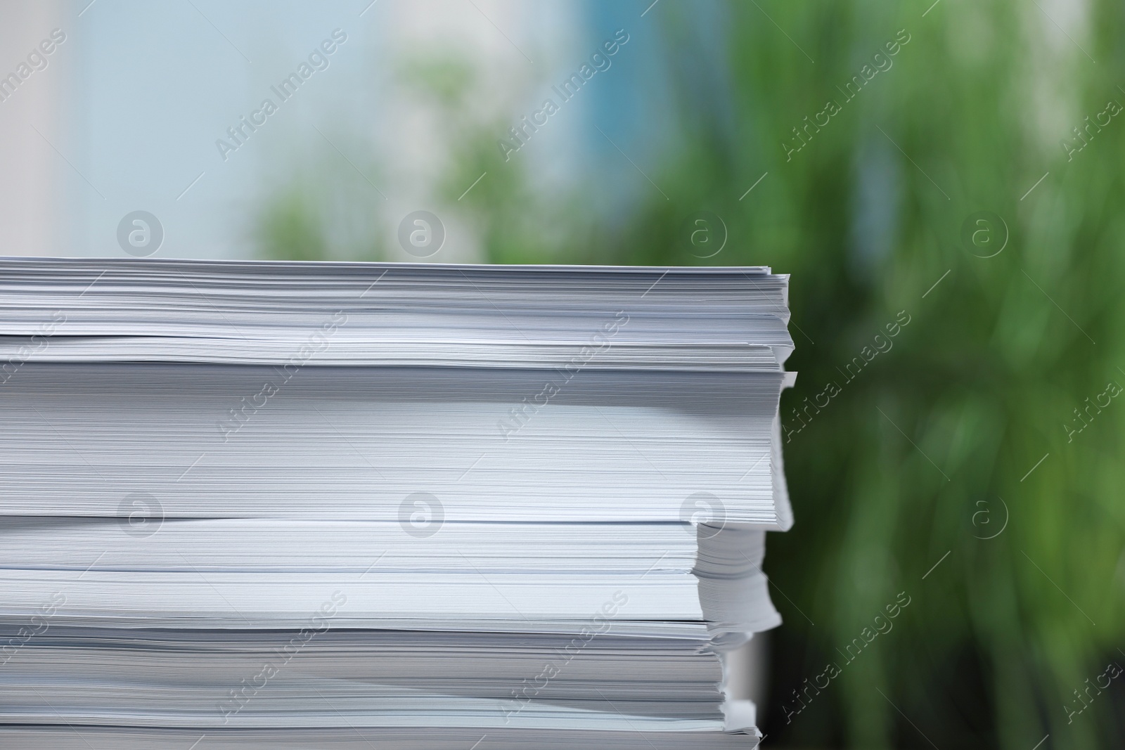 Photo of Stack of paper sheets against blurred background, closeup. Space for text