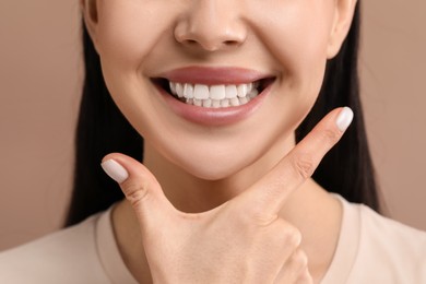 Woman with clean teeth smiling on beige background, closeup