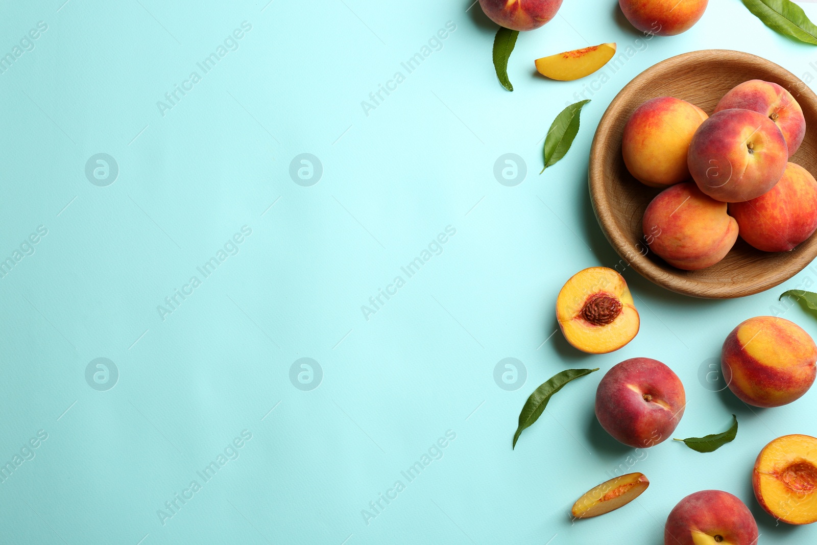 Photo of Fresh ripe peaches and green leaves on light blue background, flat lay. Space for text