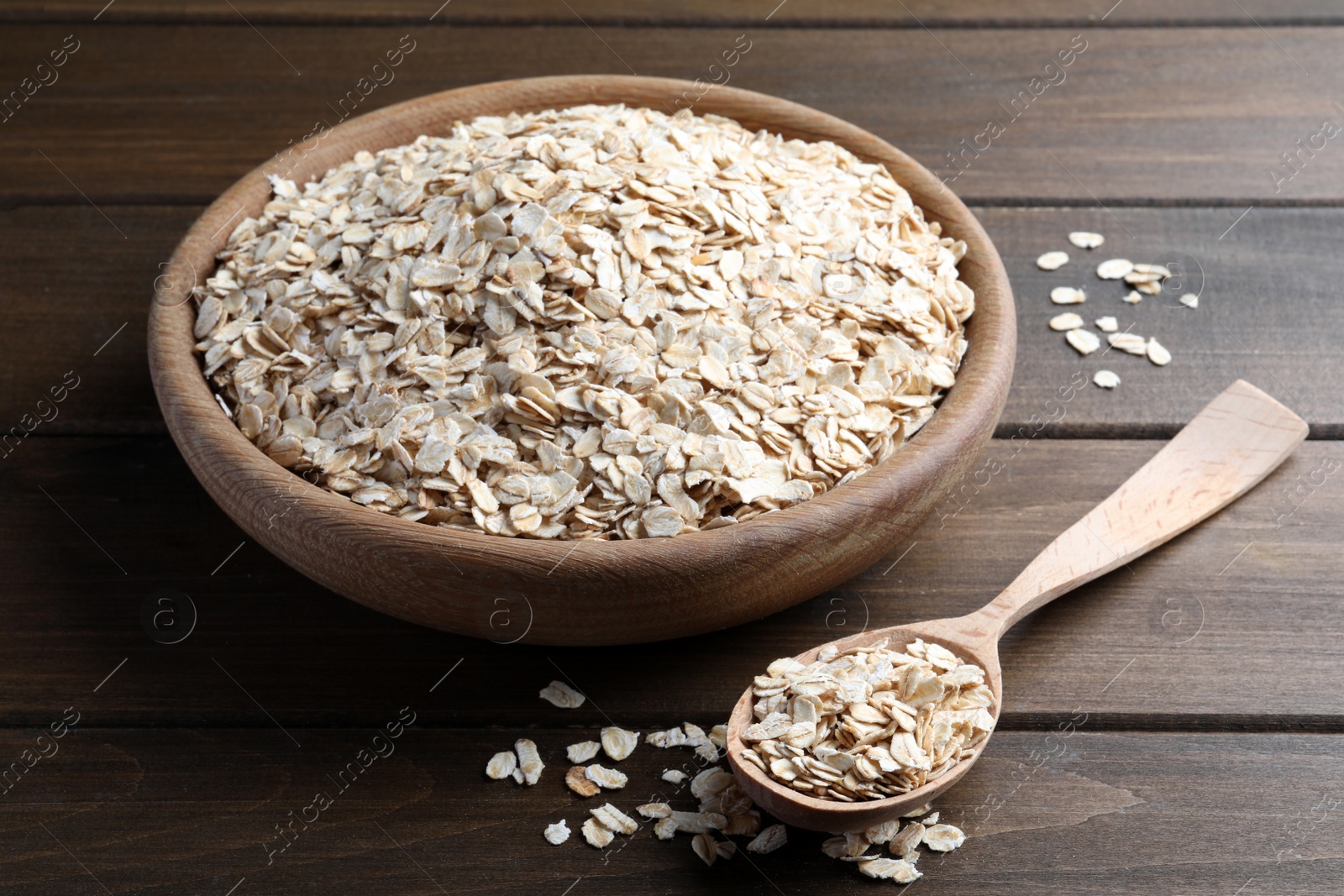 Photo of Bowl and spoon with oatmeal on wooden table