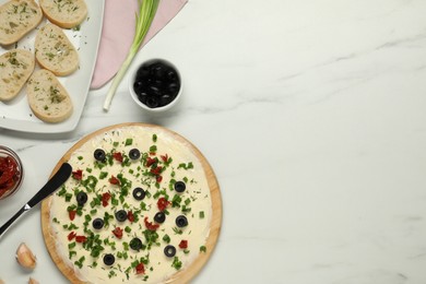 Photo of Fresh natural butter board with olives, bread and knife on white marble table, flat lay. Space for text