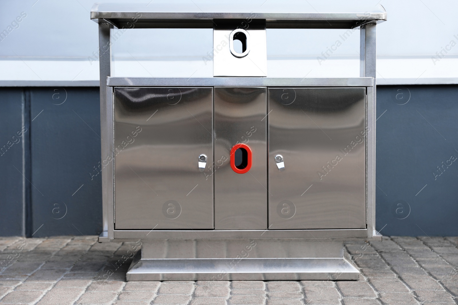 Photo of Modern metal recycling bin on street near building